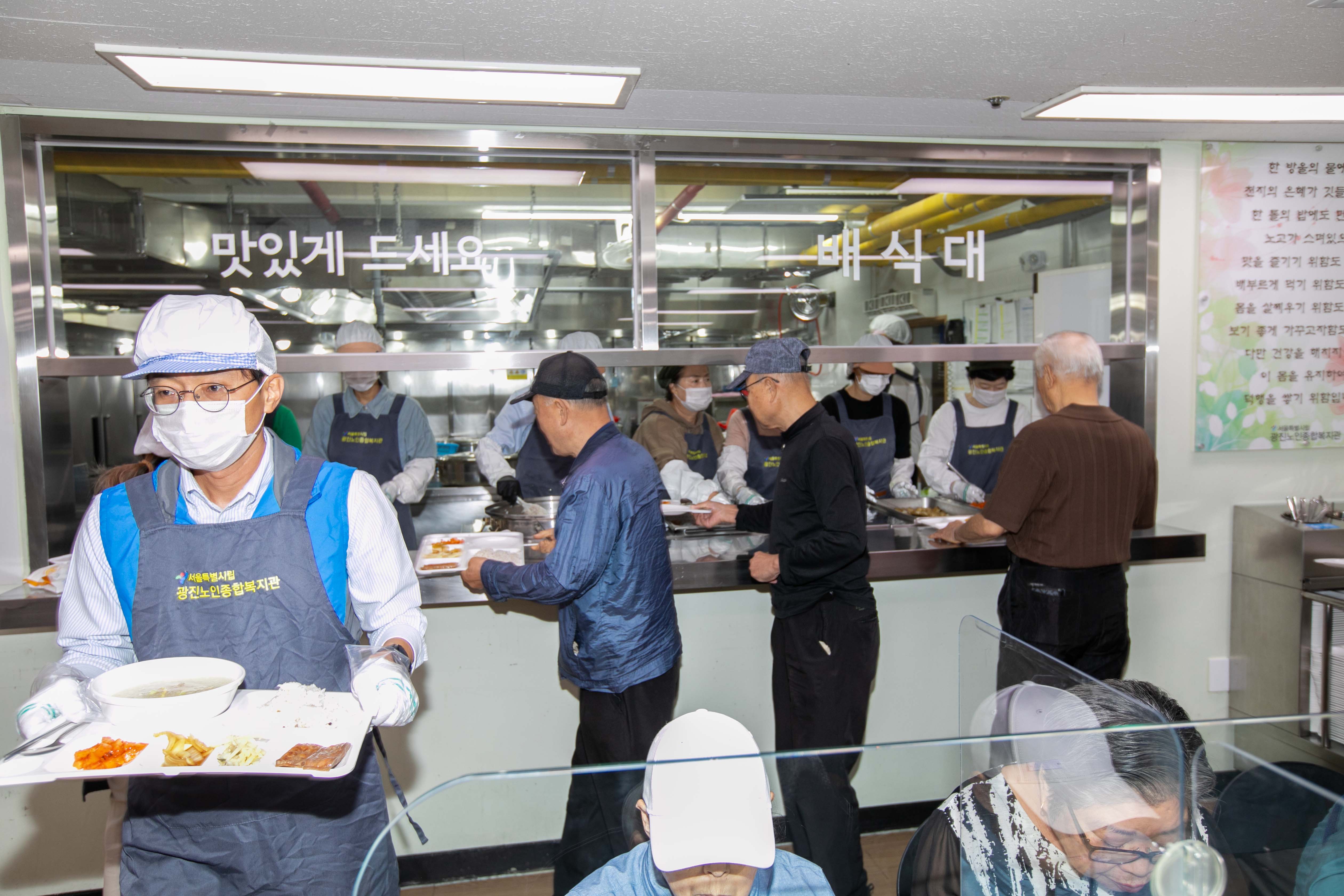 거동이 불편한 어르신들을 위해 한국사회보장정보원 임직원들이  배식을 대신 받아 어르신들이 계신 식탁으로 나르고 있다.